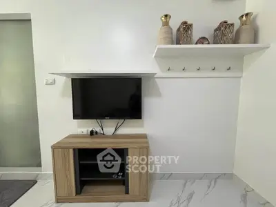 Modern living room with mounted TV and stylish decor on white walls.