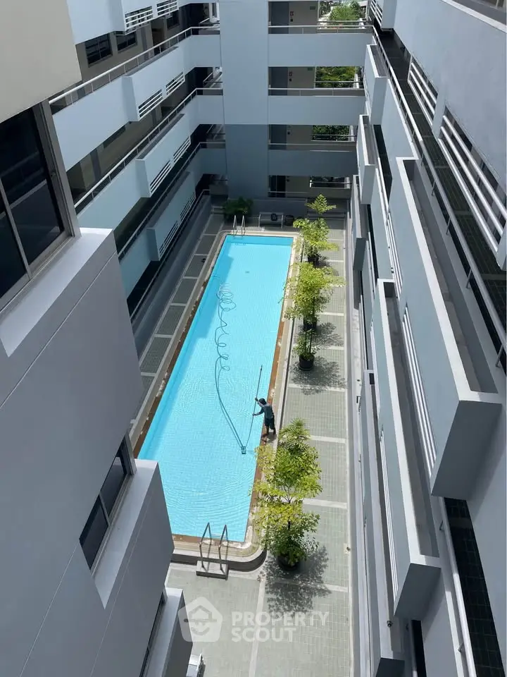 Modern apartment complex with a pristine swimming pool and lush greenery.