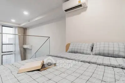 Modern bedroom with stylish bedding and air conditioning, featuring a city view.