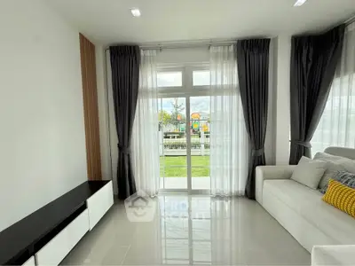 Bright living room with large windows and modern decor overlooking a lush garden.