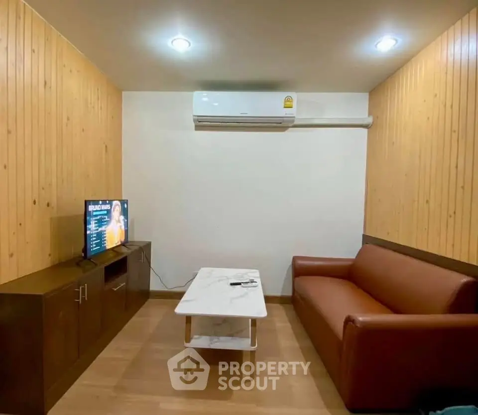 Cozy living room with modern sofa, TV, and air conditioning in a stylish wooden interior.