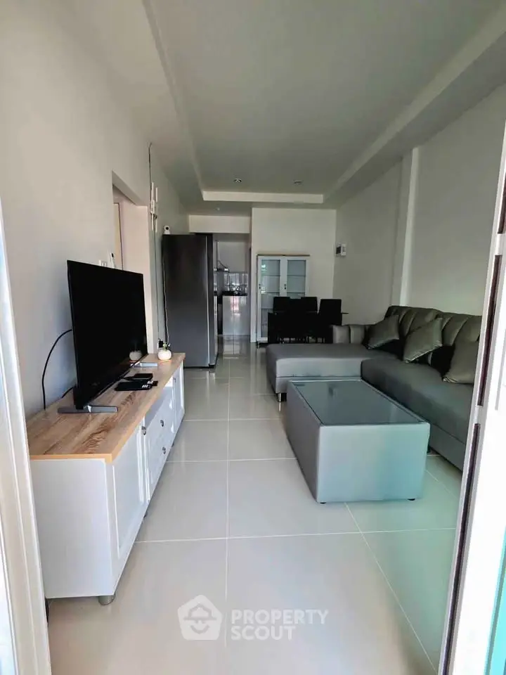 Modern living room with sleek furniture and open layout, featuring a TV and stylish decor.