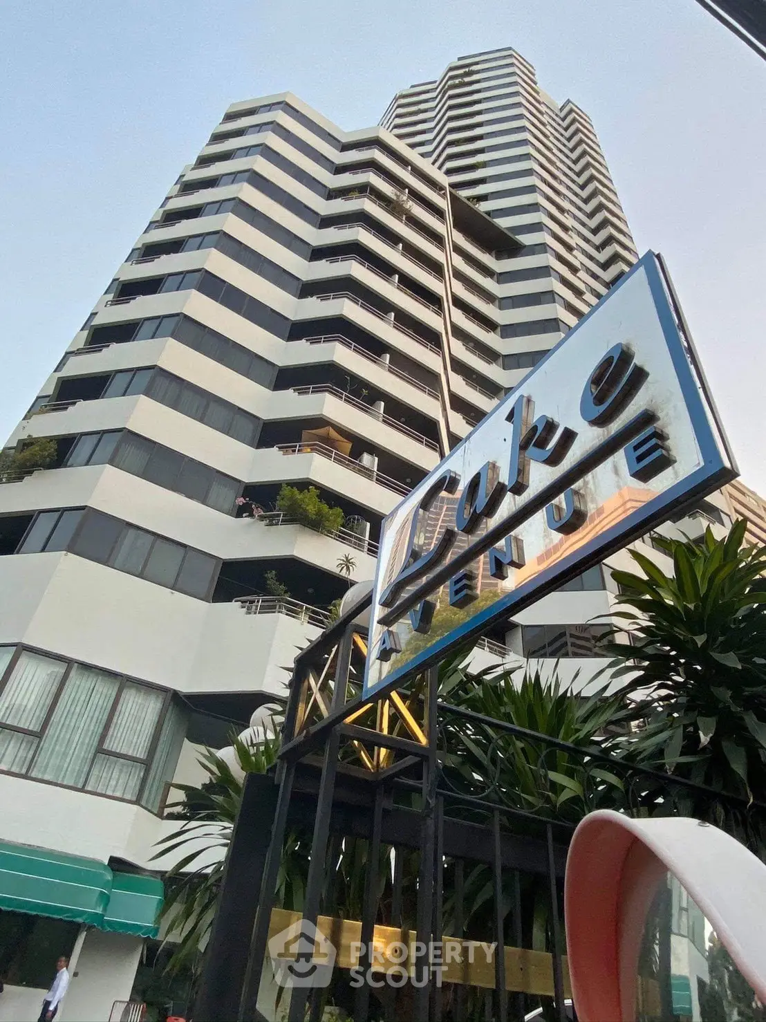 Modern high-rise building with unique architectural design and lush greenery