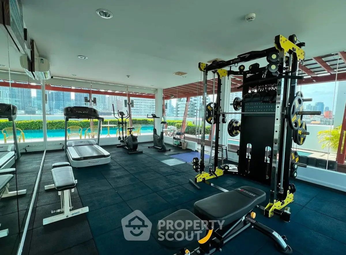 Modern gym with state-of-the-art equipment and pool view in luxury residential building.