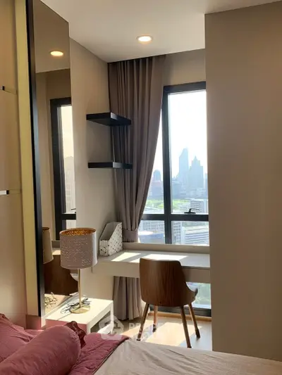 Modern bedroom with city view, featuring stylish desk and elegant decor.