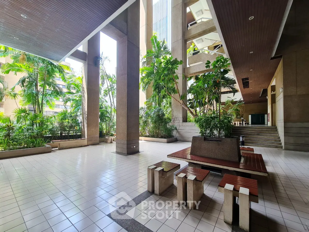 Spacious building entrance with lush greenery and seating area