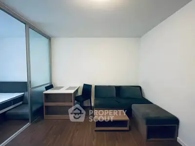 Modern living room with sleek furniture and wooden flooring, featuring a cozy sofa and a small dining area.