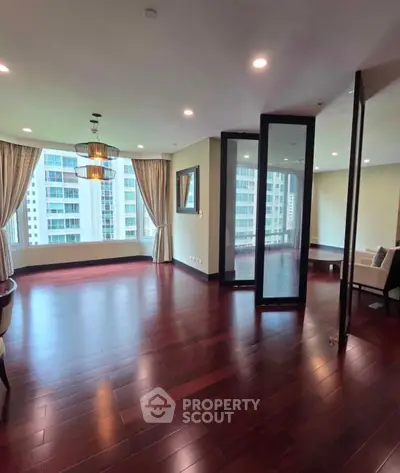 Spacious modern living room with hardwood floors and city view in luxury apartment.