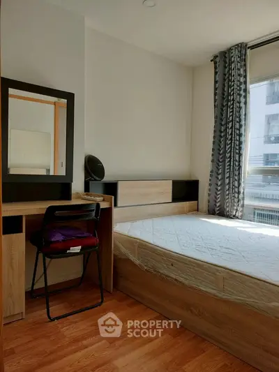 Cozy bedroom with natural light, featuring a bed, desk, and chair, ideal for comfortable living.