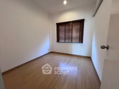 Spacious empty room with wooden flooring and window blinds, perfect for customization.
