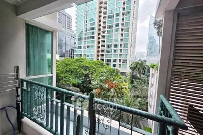 Charming balcony view with lush greenery and modern high-rise buildings in the background.