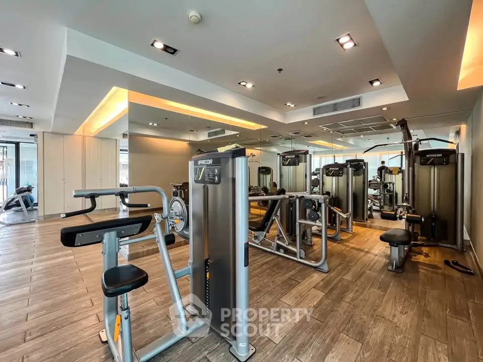 Modern gym with state-of-the-art fitness equipment and mirrored walls in luxury residential building.