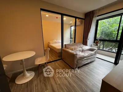 Modern apartment with cozy living room and bedroom, featuring large windows and stylish furniture.