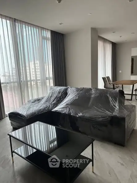 Spacious modern living room with large windows and elegant furniture, perfect for urban living.