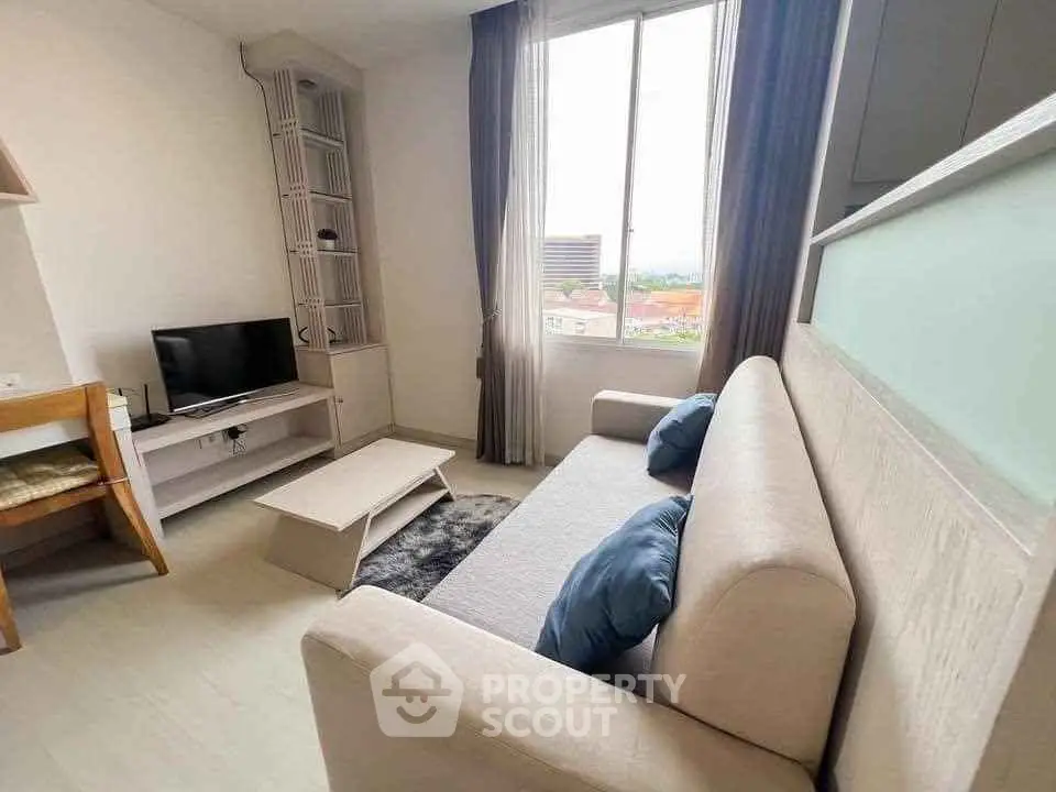 Modern living room with cozy sofa and large window offering city views.