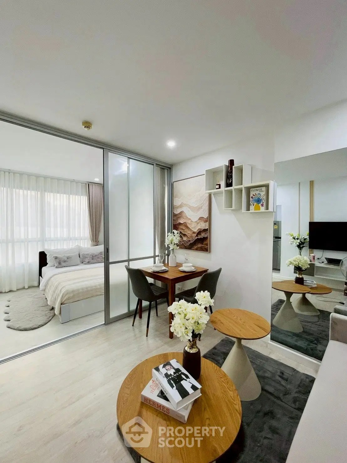 Modern open-plan living room with dining area and bedroom, featuring stylish decor and natural light.