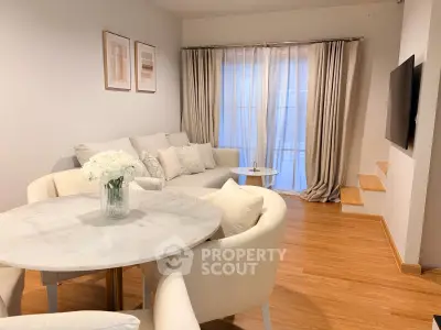 Elegant living room with cozy seating and stylish decor, featuring a modern TV setup and natural light.