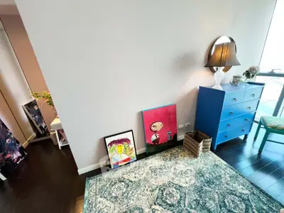 Chic living room corner with modern decor and vibrant artwork, featuring a stylish blue dresser and elegant lamp.