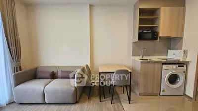 Modern compact living room with kitchenette and washing machine, perfect for urban living.