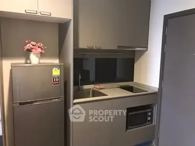 Modern compact kitchen with sleek cabinetry and built-in appliances in a stylish apartment.