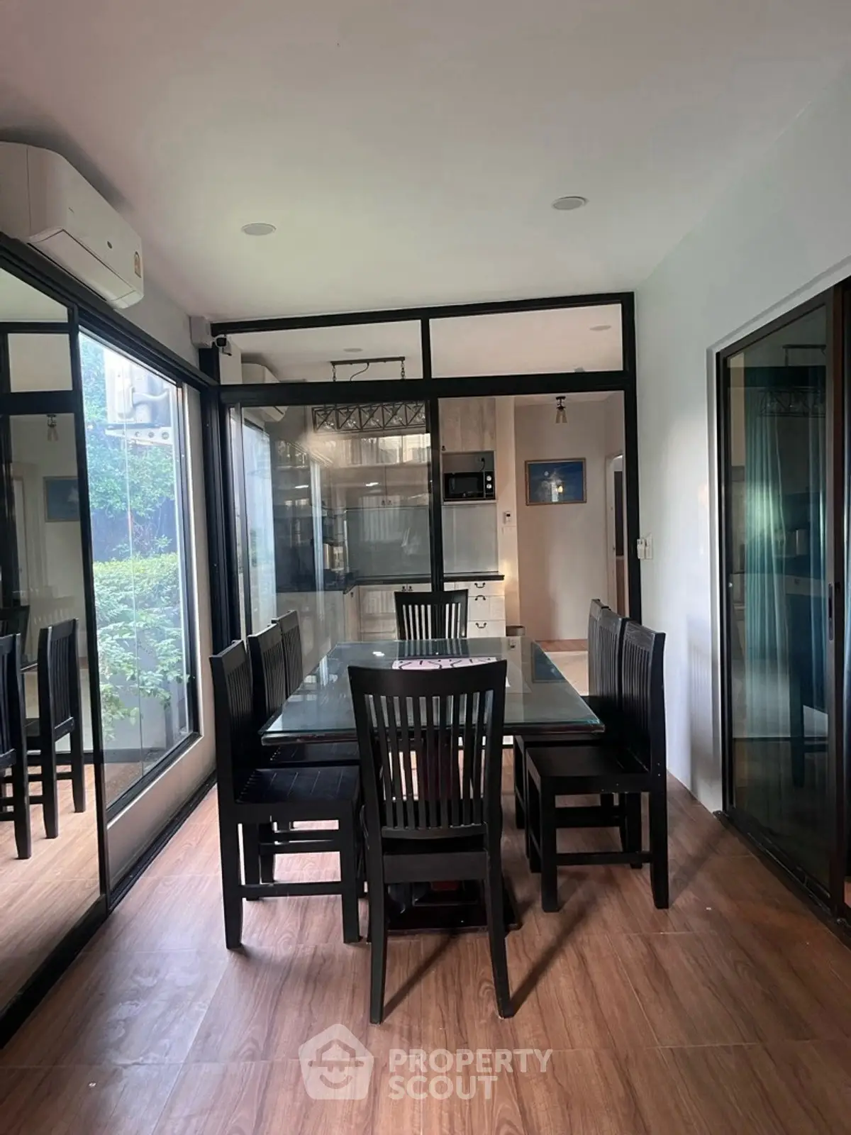 Stylish dining area with glass table and black chairs, adjacent to modern kitchen.
