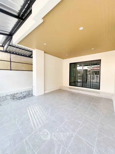 Spacious modern patio with tiled flooring and large window, perfect for outdoor relaxation.