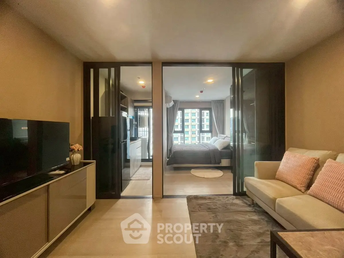 Modern living room with sliding glass doors leading to a cozy bedroom, featuring stylish decor.