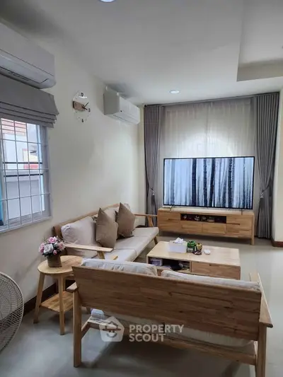 Cozy living room with modern wooden furniture and large TV, perfect for relaxation.