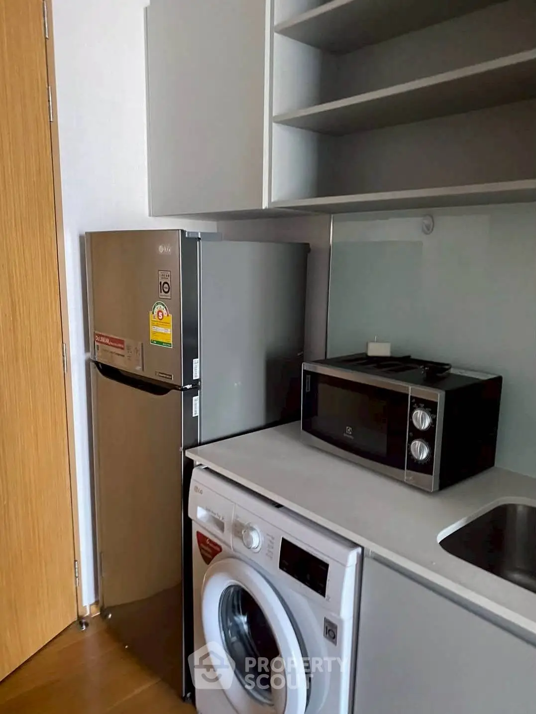 Compact kitchen with modern appliances including fridge, microwave, and washing machine.