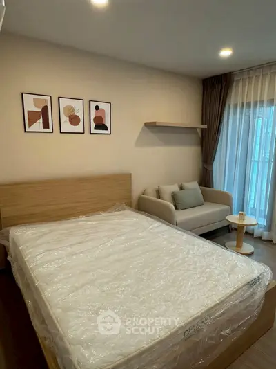 Modern bedroom with stylish decor, cozy sofa, and natural light from large window.