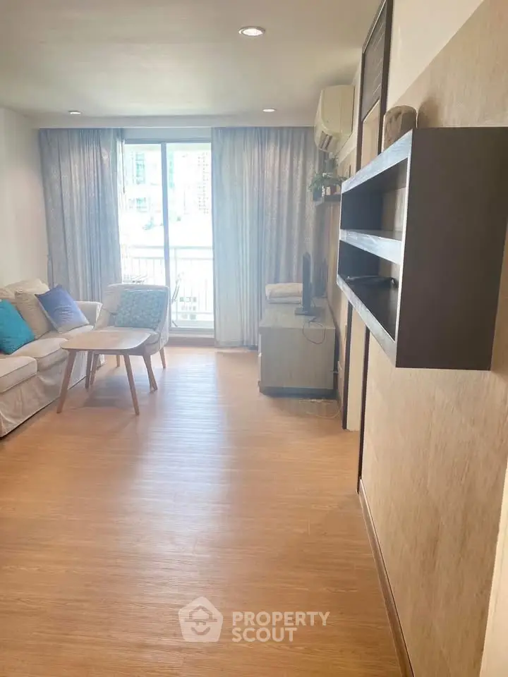 Spacious living room with modern decor and large window offering natural light.