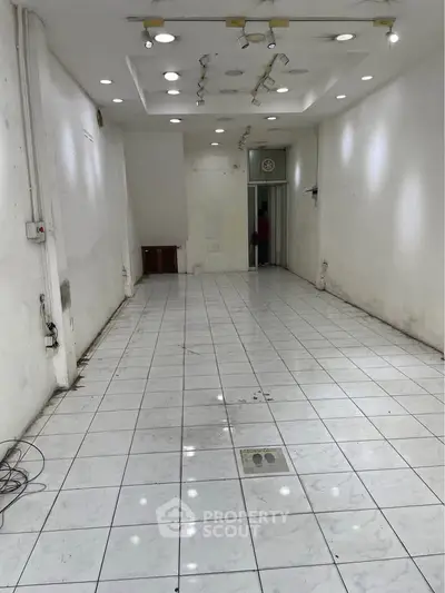 Spacious commercial space with tiled flooring and recessed lighting, ideal for retail or office use.