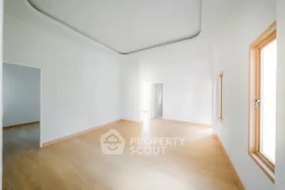 Spacious empty room with wooden flooring and natural light