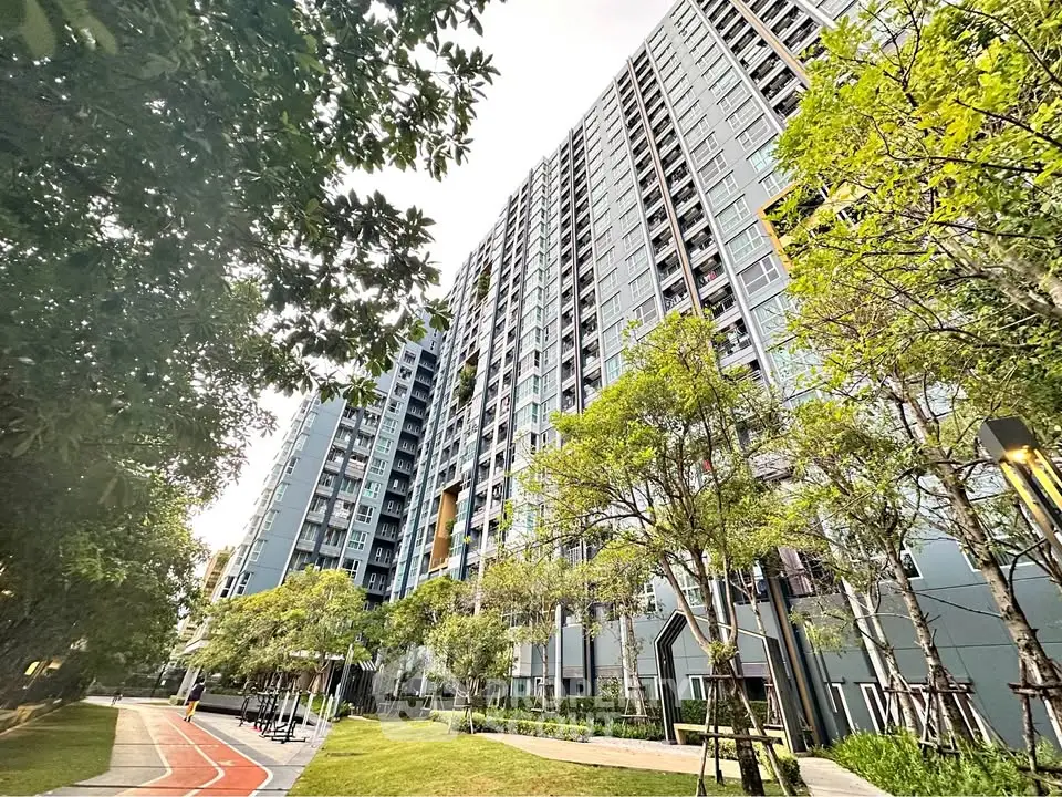 Modern high-rise residential building with lush green surroundings and walking path.
