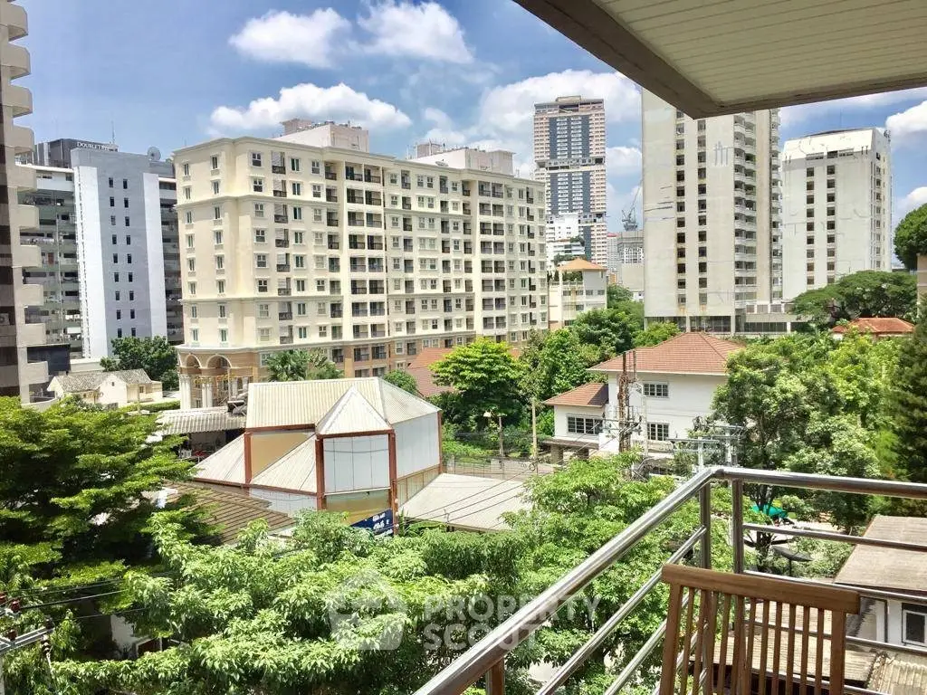 Stunning urban view from a modern balcony overlooking lush greenery and cityscape.