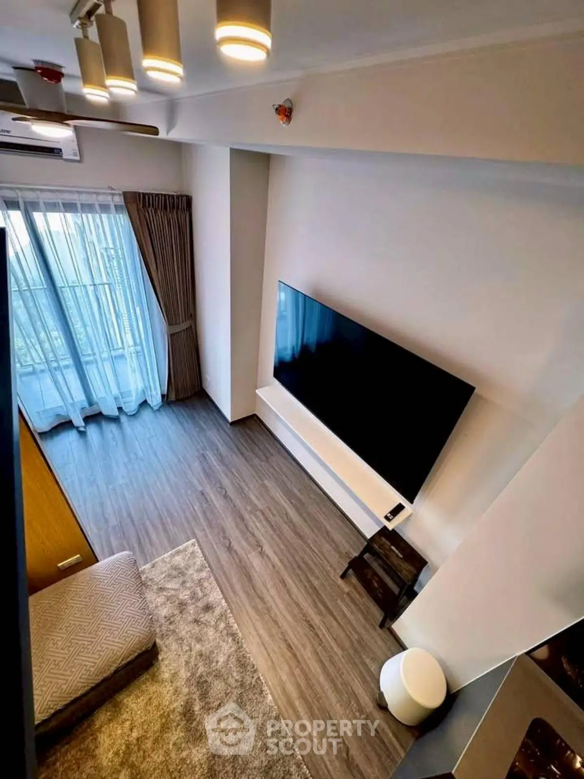 Modern living room with large TV and stylish decor, featuring floor-to-ceiling windows and elegant lighting.
