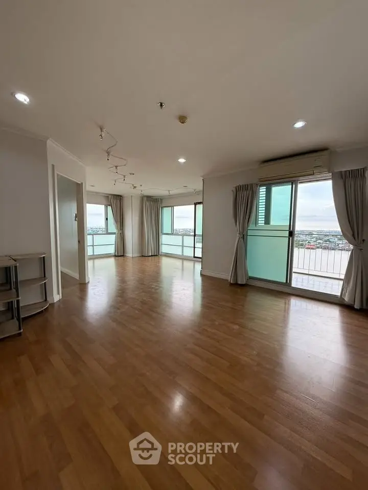 Spacious living room with wooden flooring and large windows offering stunning views.