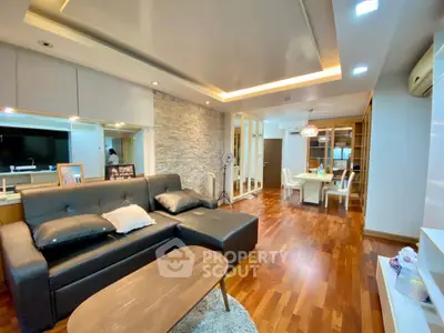 Modern living room with elegant decor and open dining area, featuring hardwood floors and stylish lighting.