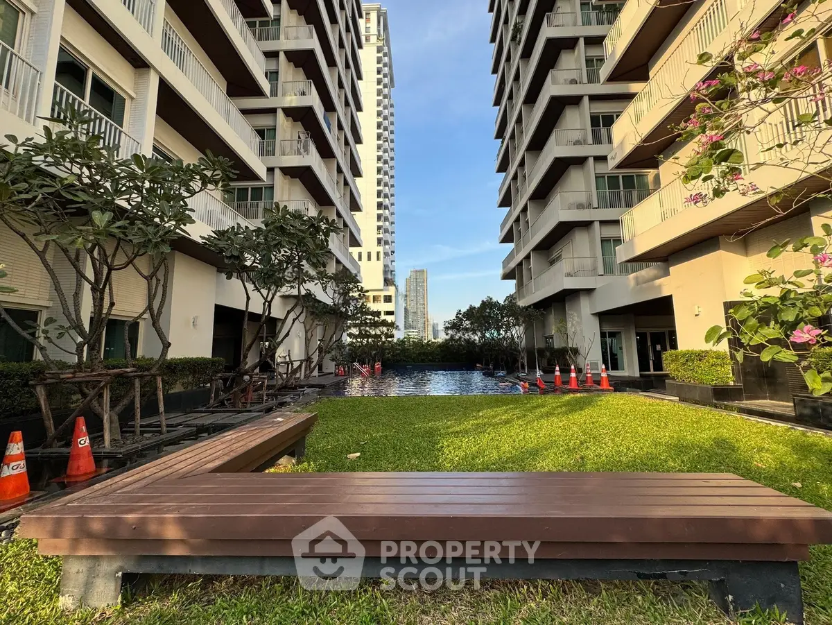 Luxurious residential building with lush garden and pool view, perfect for urban living.