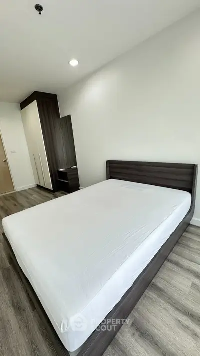 Spacious modern bedroom with sleek wooden flooring and minimalist design.