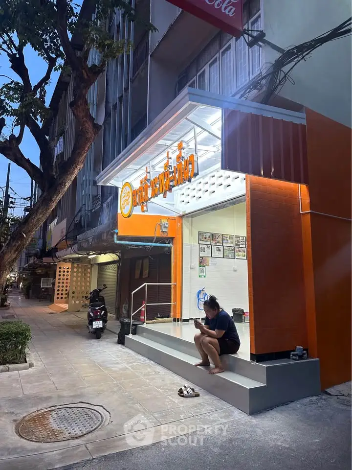 Charming street view of a modern storefront with vibrant orange accents and inviting entrance.