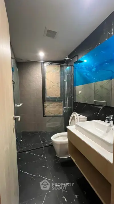Modern bathroom with sleek black tiles and glass shower enclosure