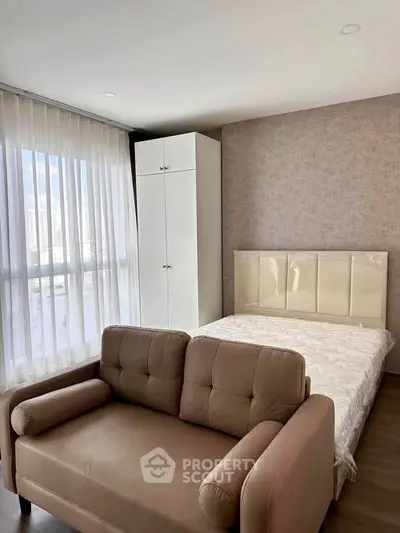 Modern bedroom with cozy sofa and large window in stylish apartment