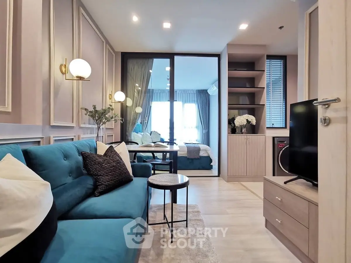 Modern living room with blue sofa and open layout leading to bedroom, stylish decor.