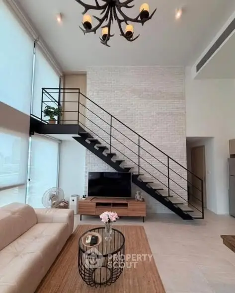 Modern living room with high ceiling, stylish staircase, and elegant decor in a contemporary apartment.