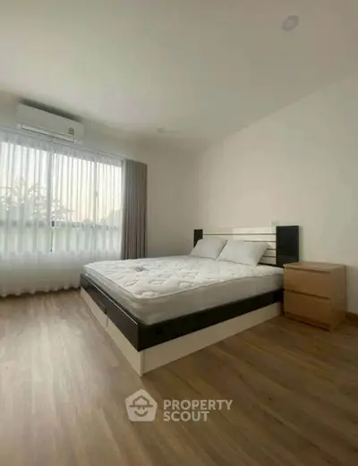 Spacious bedroom with large window and modern furnishings, perfect for relaxation.