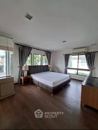 Spacious bedroom with large windows and modern furnishings in a well-lit home.