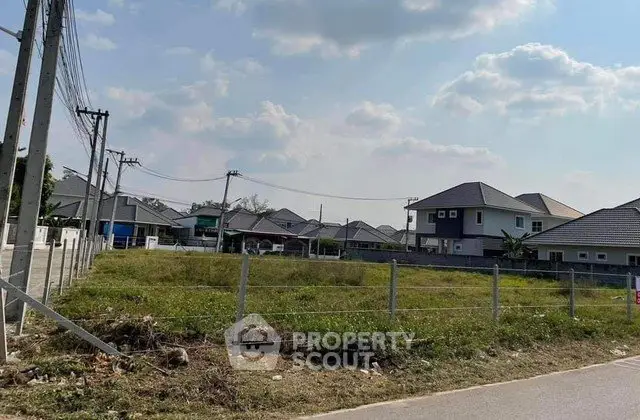 Prime residential land for sale in a serene neighborhood with modern houses and clear skies.