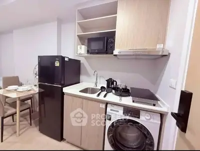 Modern kitchen with appliances including fridge, microwave, and washing machine in compact layout.