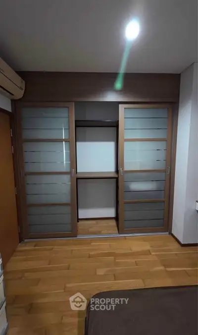 Spacious bedroom with wooden flooring and sliding closet doors, perfect for modern living.